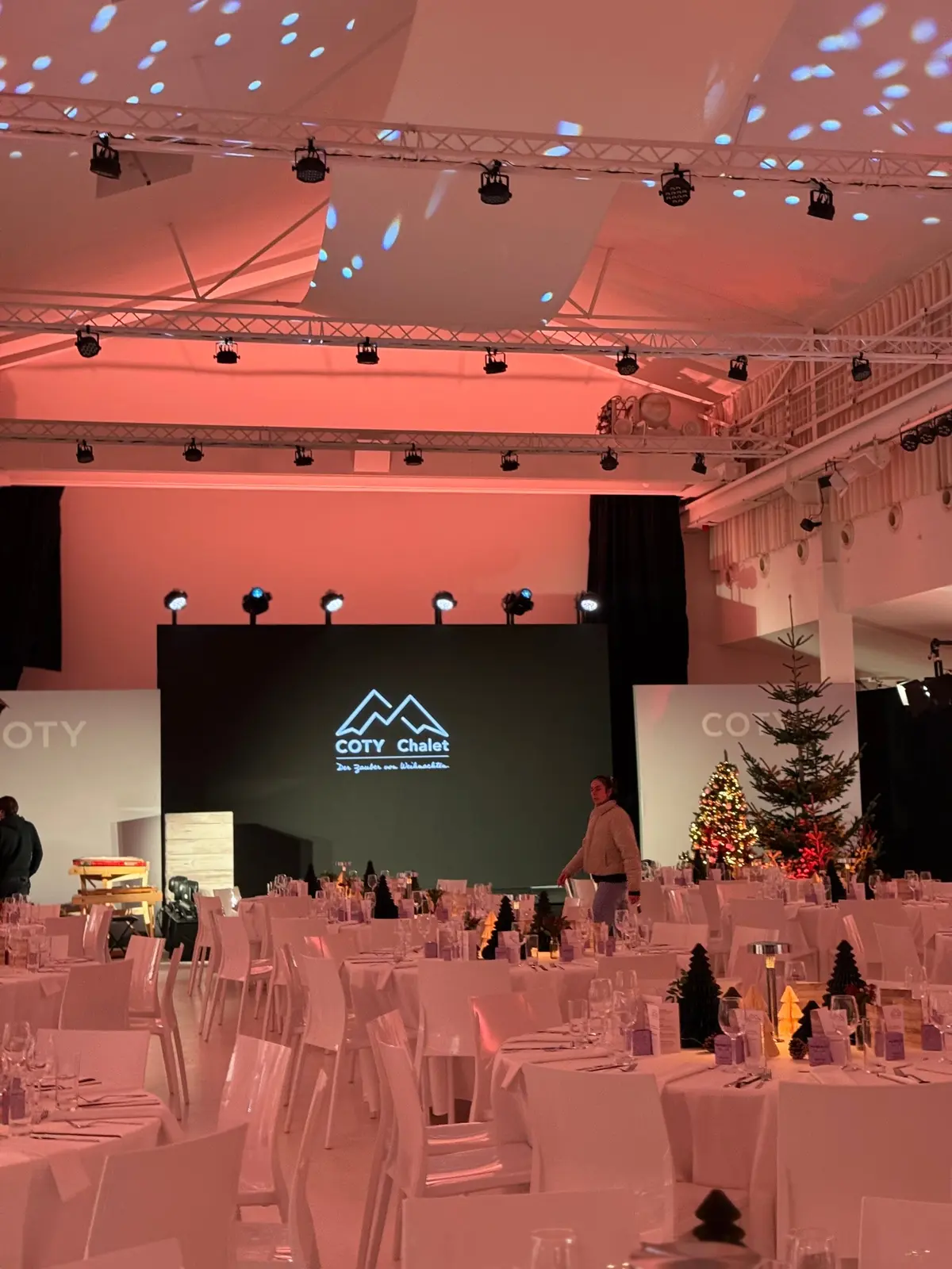 Firmen-Weihnachtsgala mit runden Tafeln vor der Bühne mit LED-Wand und Tannenbäumen