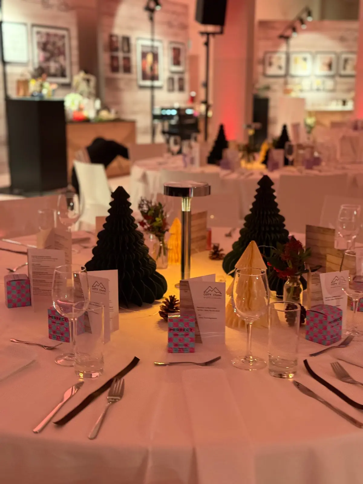 Weihnachtlich gedeckte runde Tafel mit Papier-Tannenbäumen und Tischleuchte im B2LOFT